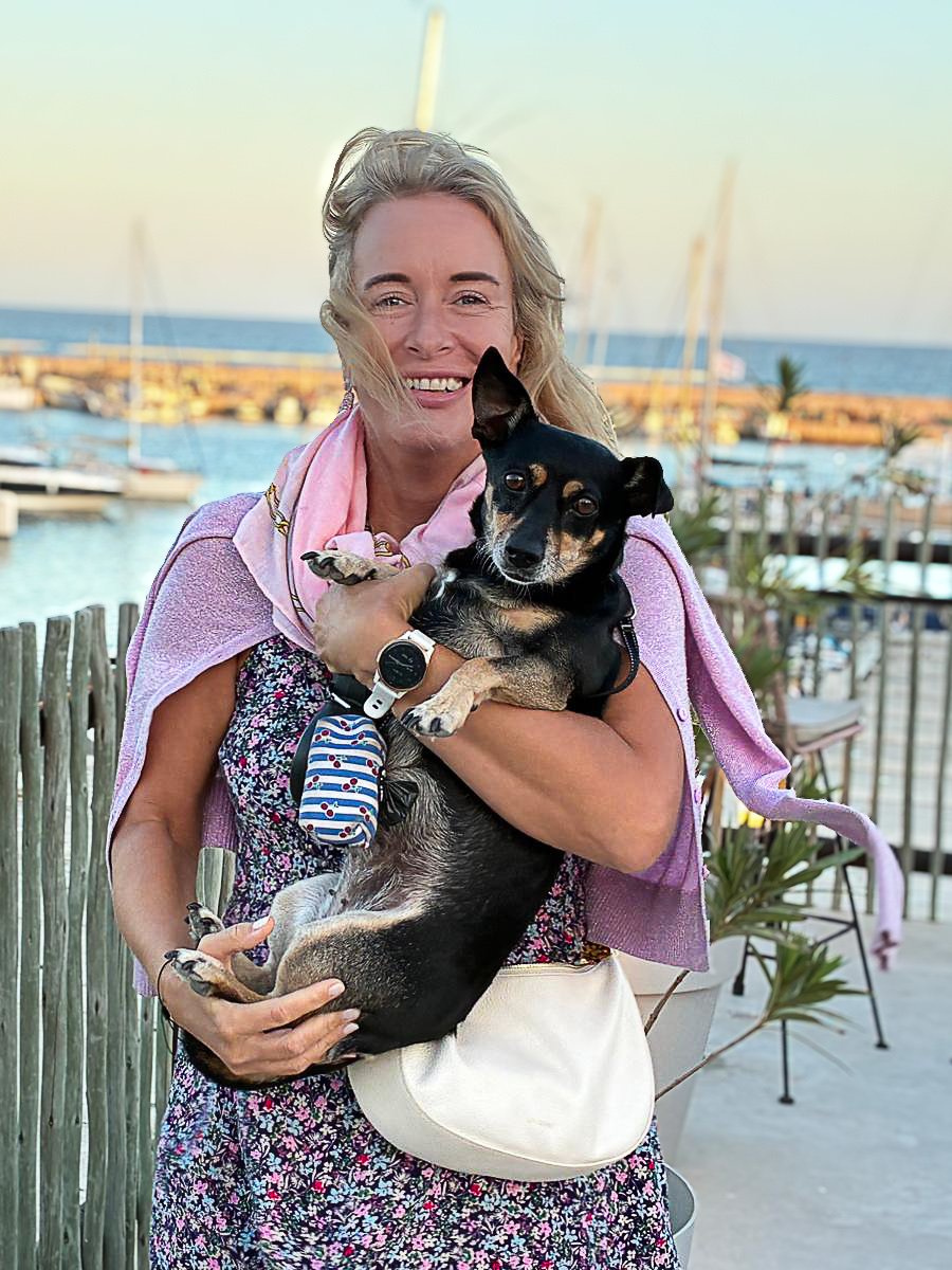 Valerie Nuyttens holding her dog by the marina